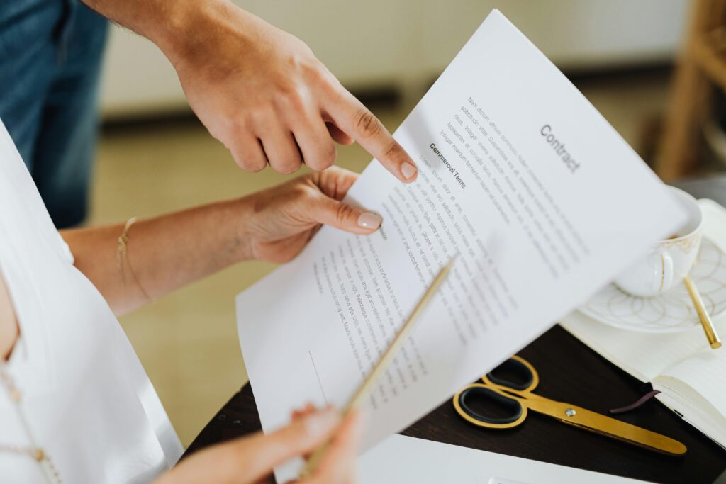 Close-up of two people discussing a business contract at a desk in an office setting.