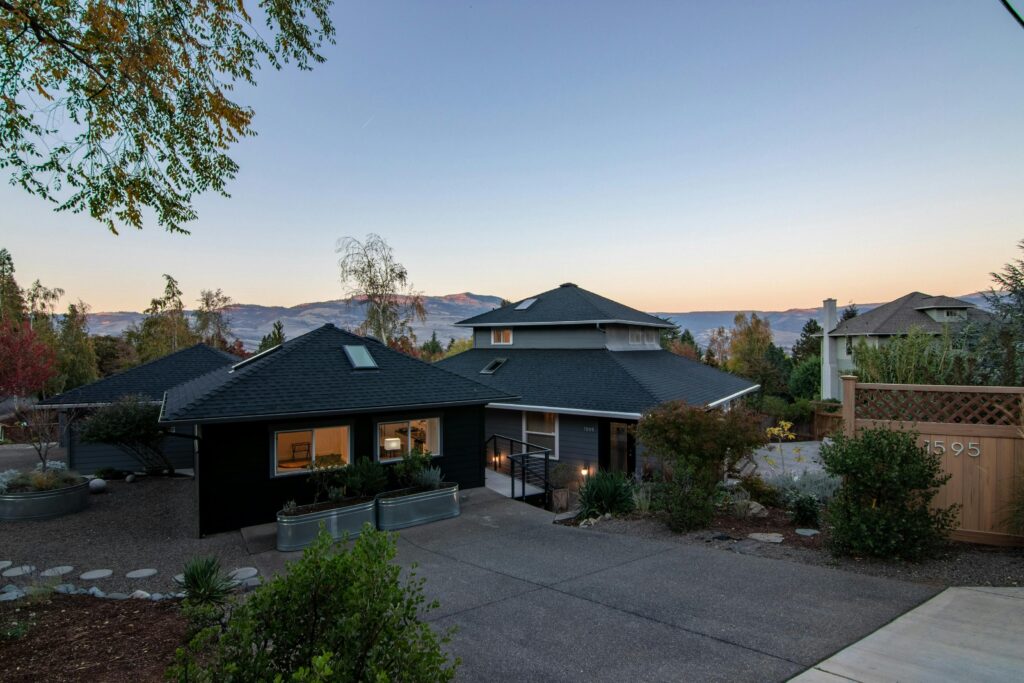 Elegant suburban house with spacious driveway and stunning mountain views at sunset.