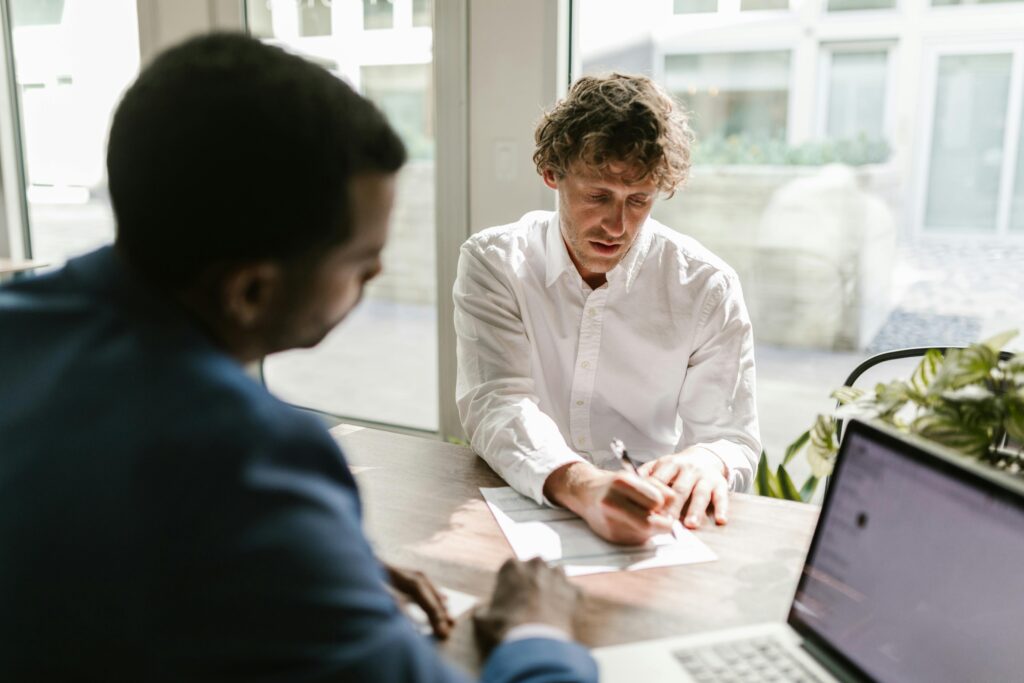 Two men collaborating in a modern office, reviewing and signing documents.