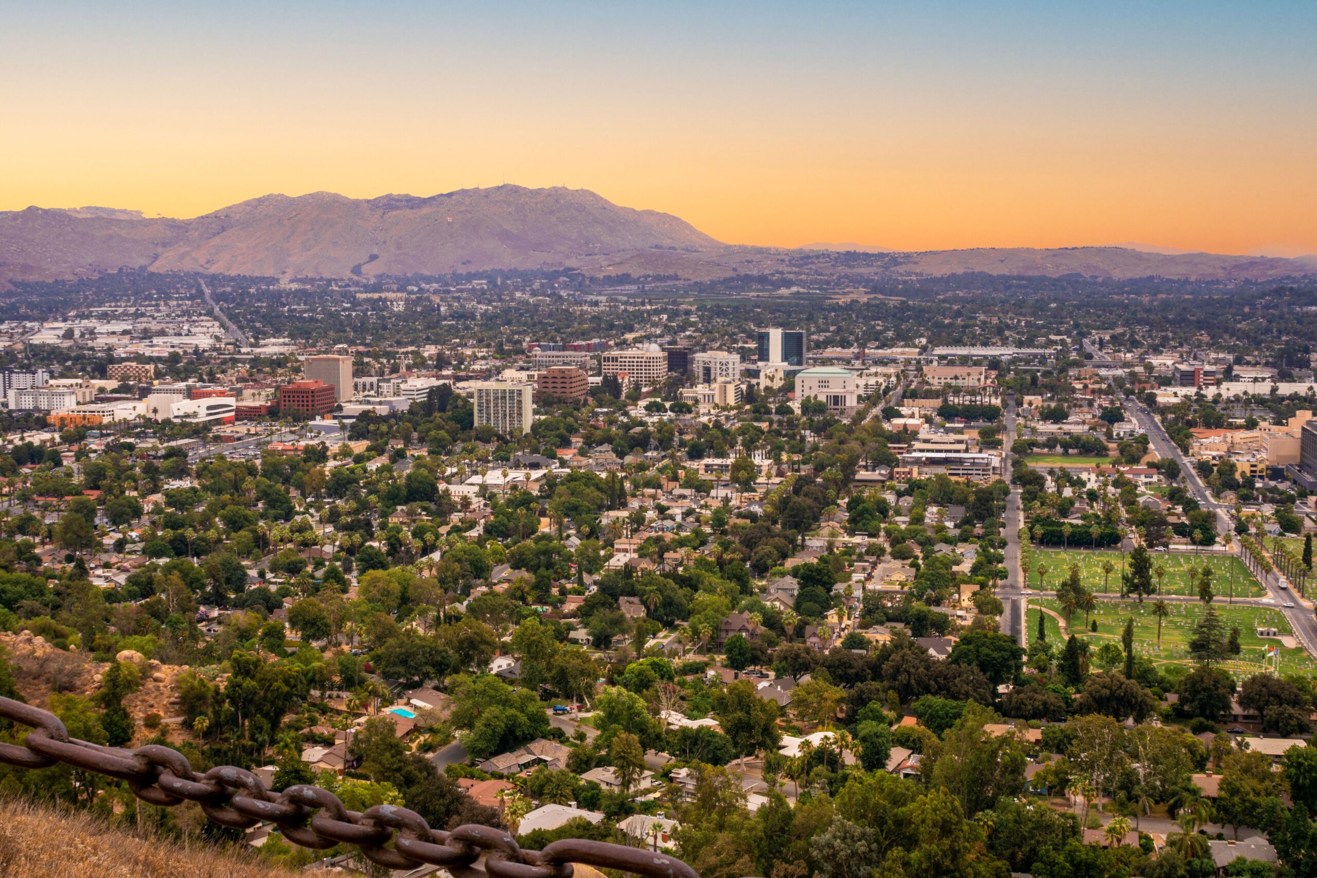 Stunning aerial view of Riverside cityscape, with mountains in the background under a twilight sky.