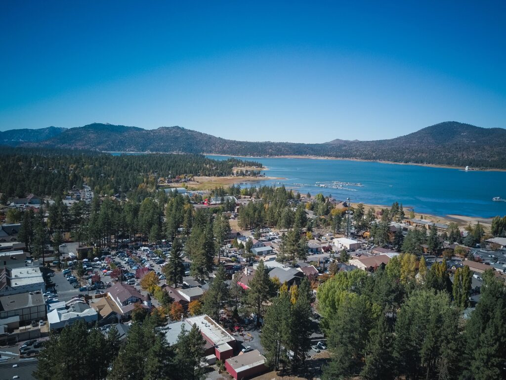 A serene aerial view of a town by a lake surrounded by mountains and nature.